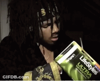 A Man Is Holding A Pack Of Lifestyles Ultra Sensitive Condoms GIF