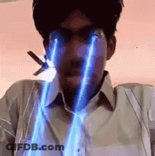 A Man Is Holding A Pair Of Scissors In His Mouth And His Eyes Are Glowing In Blue Light . GIF
