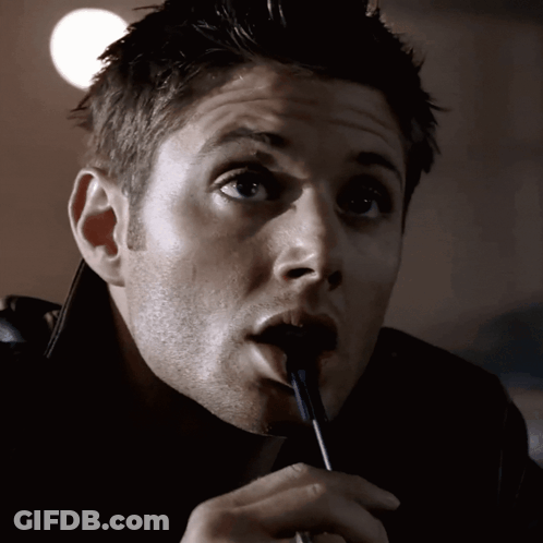 A Man Is Holding A Pen In His Mouth And Looking At The Camera GIF