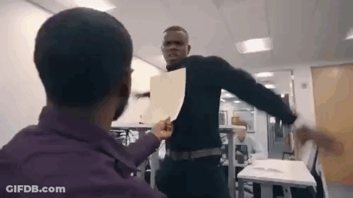 A Man Is Holding A Piece Of Paper In Front Of Another Man In An Office . GIF