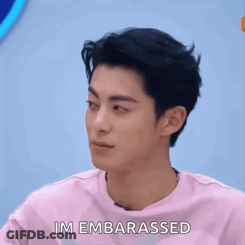 A Man Is Holding A Piece Of Paper In Front Of His Face And Making A Funny Face . GIF