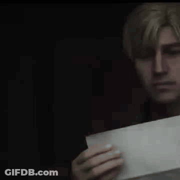 A Man Is Holding A Piece Of Paper In His Hand And Looking At It . GIF