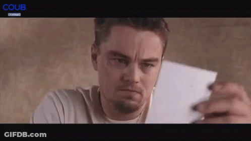 A Man Is Holding A Piece Of Paper In His Hand And Making A Face . GIF