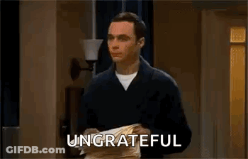 A Man Is Holding A Piece Of Paper In His Hands And The Word Ungrateful Is On The Screen . GIF