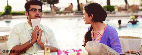A Man Is Holding A Piece Of Paper In His Mouth And A Woman Is Looking At Him GIF