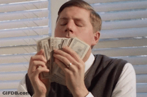 A Man Is Holding A Pile Of Money In His Mouth GIF