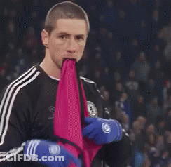 A Man Is Holding A Pink Cloth In His Mouth While Wearing Blue Gloves . GIF