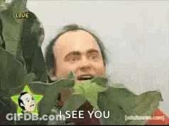 A Man Is Holding A Plant In Front Of His Face And Says `` I See You '' . GIF