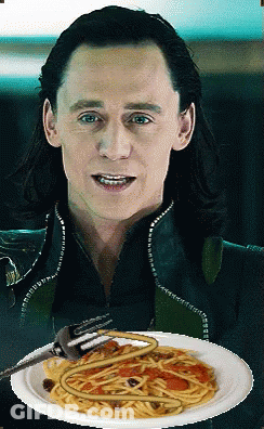 A Man Is Holding A Plate Of Spaghetti With A Fork In His Mouth GIF