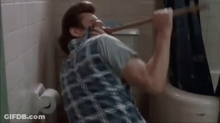 A Man Is Holding A Plunger In His Mouth While Sitting In A Bathroom . GIF