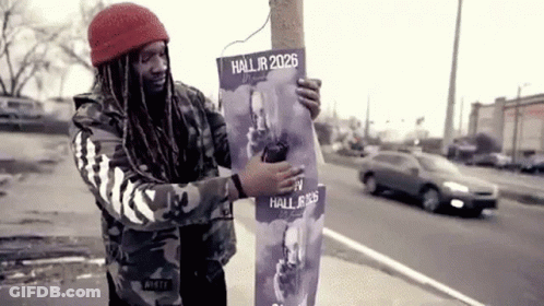 A Man Is Holding A Poster That Says Hall Jr 2026 GIF