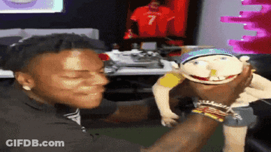 A Man Is Holding A Puppet With A Number 7 On It GIF