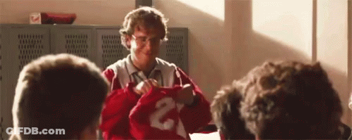 A Man Is Holding A Red Jersey With The Number 2 On It In Front Of A Group Of People . GIF