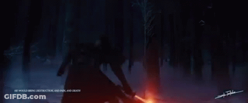 A Man Is Holding A Red Lightsaber In The Dark . GIF