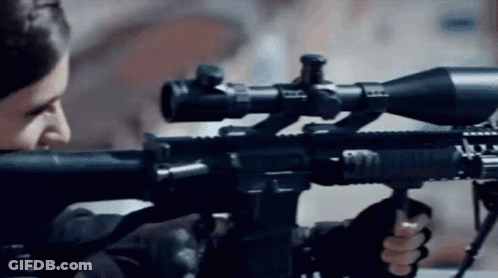 A Man Is Holding A Rifle With A Sniper Scope On It . GIF