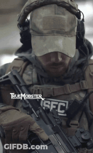 A Man Is Holding A Rifle With The Letters Sfc On His Chest GIF