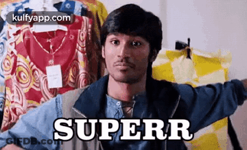 A Man Is Holding A Shirt In Front Of A Row Of Clothes And The Word Superr Is On The Shirt . GIF