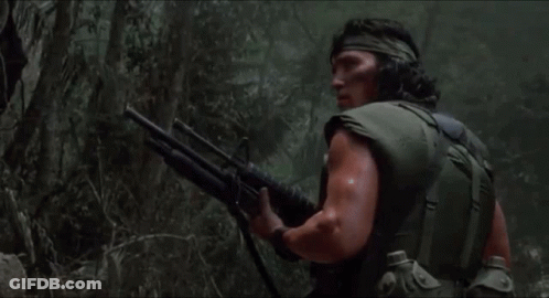 A Man Is Holding A Shotgun In The Woods GIF