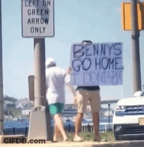 A Man Is Holding A Sign That Says Bennys Go Home GIF