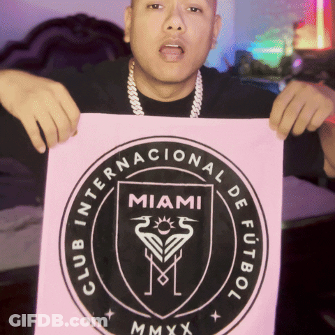 A Man Is Holding A Sign That Says Club Internacional De Futbol Miami Mmxx GIF