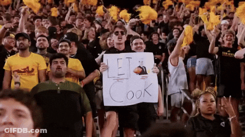 A Man Is Holding A Sign That Says Let Cook GIF