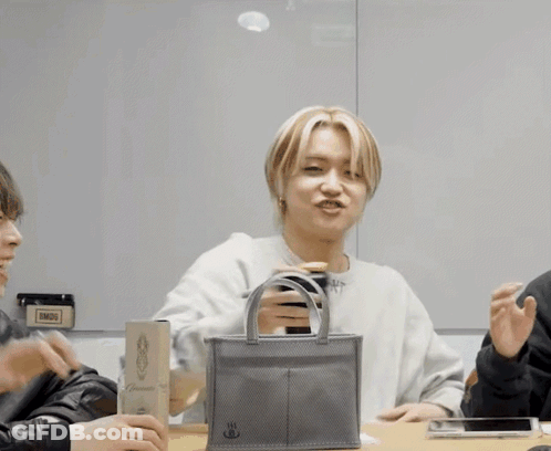 A Man Is Holding A Small Bag That Says ' Bmdg ' On It GIF