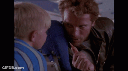 A Man Is Holding A Small Child 'S Face While Sitting On A Plane GIF