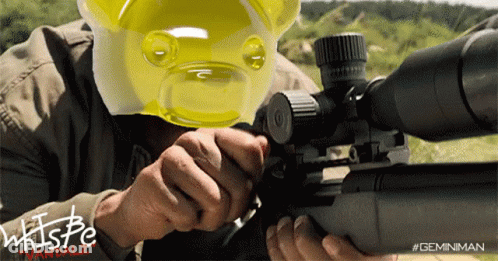 A Man Is Holding A Sniper Rifle And Wearing A Yellow Gummy Bear Mask GIF