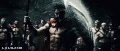 A Man Is Holding A Spear In Front Of A Group Of Spartans . GIF