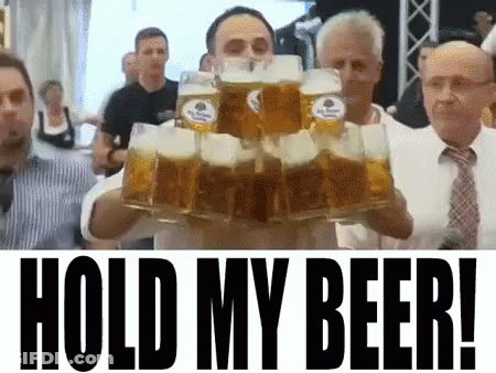 A Man Is Holding A Stack Of Beer Mugs With The Words Hold My Beer Written Below Him GIF
