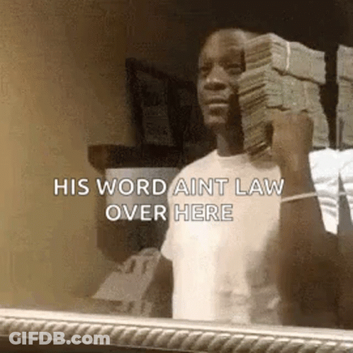 A Man Is Holding A Stack Of Money In Front Of A Mirror And Saying `` His Word Aint Law Over Here '' . GIF