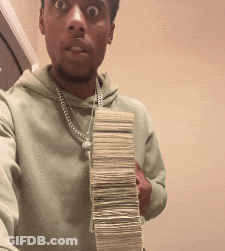 A Man Is Holding A Stack Of Money In His Hand GIF