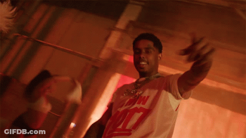 A Man Is Holding A Stack Of Money In His Hands And Wearing A White Shirt With The Number 7 On The Front GIF