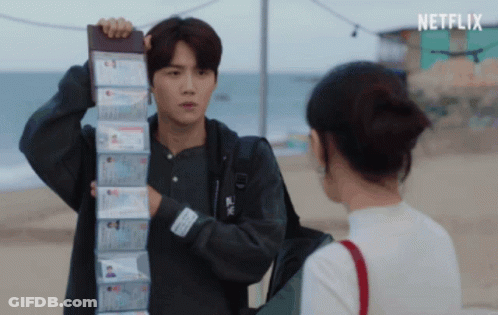 A Man Is Holding A Stack Of Passports In Front Of A Woman And The Word Netflix Is On The Bottom Right GIF