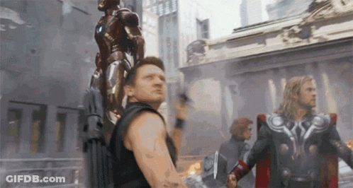 A Man Is Holding A Statue Of Iron Man On His Back And Thor Is Standing Next To Him . GIF