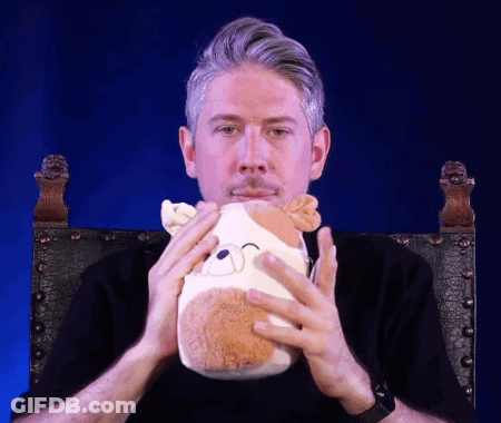 A Man Is Holding A Stuffed Animal In His Hands GIF