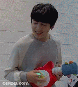 A Man Is Holding A Stuffed Animal In His Hands And Smiling GIF