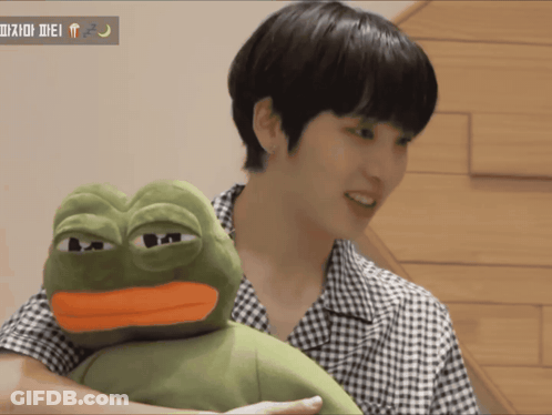 A Man Is Holding A Stuffed Frog With A Yellow Beak GIF