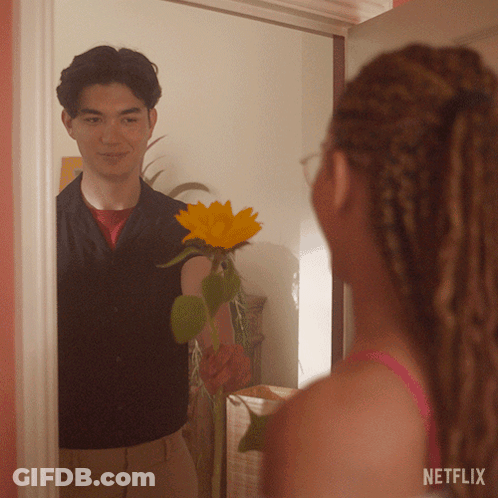 A Man Is Holding A Sunflower In Front Of A Mirror With A Netflix Logo On The Bottom GIF