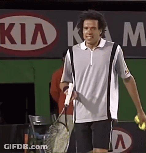 A Man Is Holding A Tennis Racquet And A Tennis Ball In Front Of A Kia Sign GIF