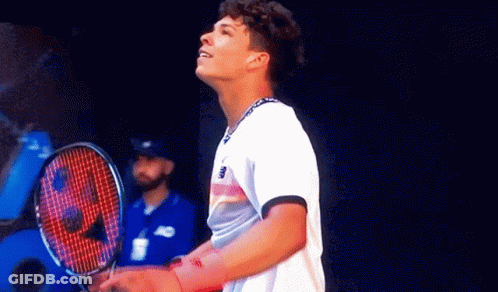 A Man Is Holding A Tennis Racquet And Looking Up GIF