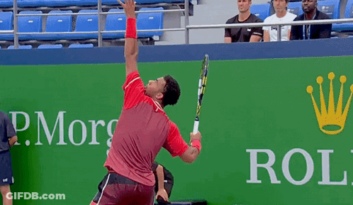 A Man Is Holding A Tennis Racquet In Front Of A Rolex Ad GIF
