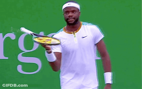 A Man Is Holding A Tennis Racquet In Front Of A Sign That Says Rgs GIF
