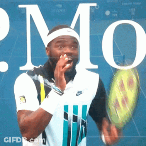 A Man Is Holding A Tennis Racquet In Front Of A Sign That Says Us Open GIF