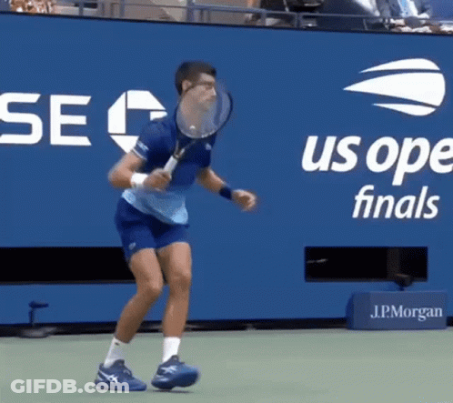 A Man Is Holding A Tennis Racquet In Front Of A Us Open Finals Banner GIF