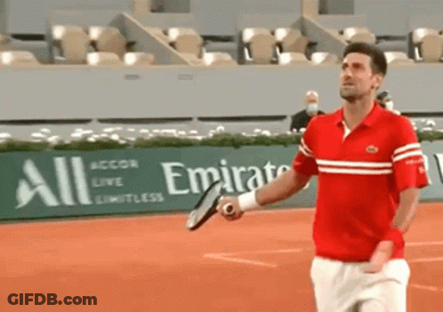 A Man Is Holding A Tennis Racquet In Front Of An Emirates Sign GIF