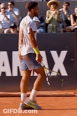 A Man Is Holding A Tennis Racquet On A Court In Front Of A Sign That Says Army GIF