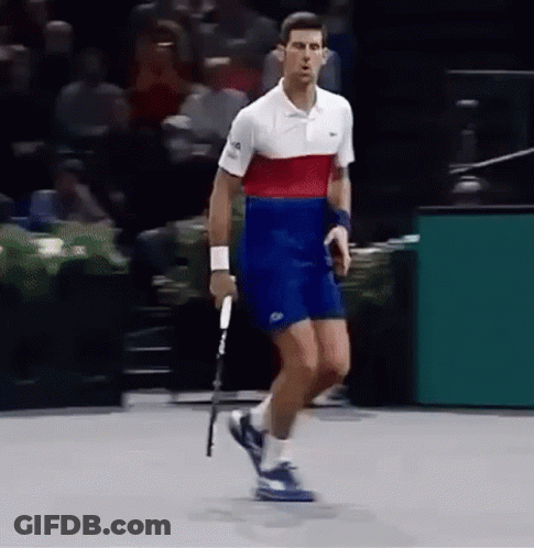 A Man Is Holding A Tennis Racquet On A Court . GIF