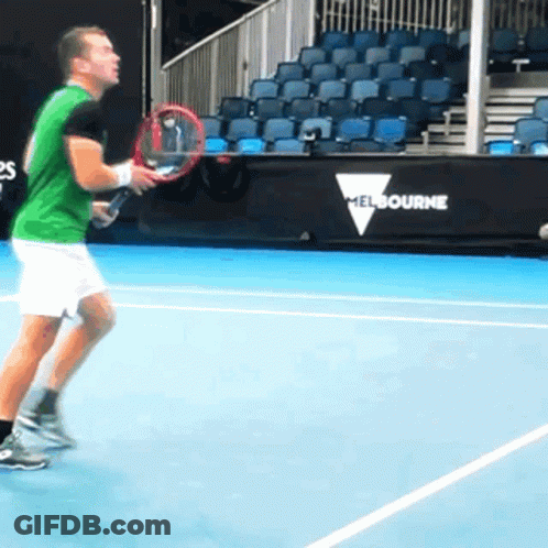 A Man Is Holding A Tennis Racquet On A Court With A Melbourne Sign Behind Him GIF
