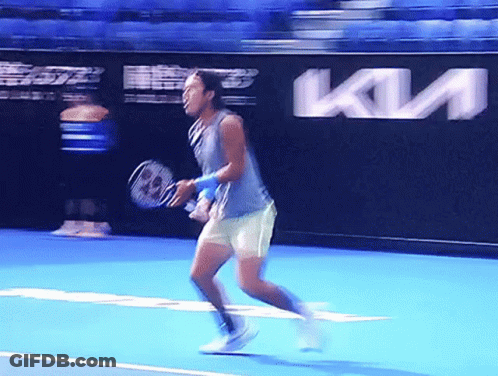 A Man Is Holding A Tennis Racquet On A Tennis Court In Front Of A Kia Ad GIF